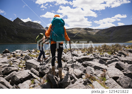 Two women hiking on high altitude mountains, walking to a beautiful lake 125421822