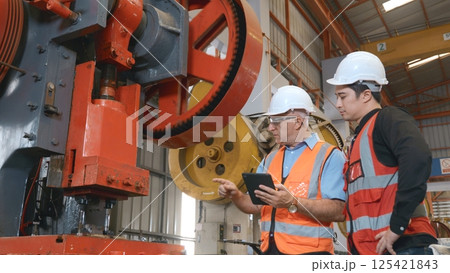 Two engineers talking together in roof steel metal manufacturing factory industry, engineering worker man standing explaining for maintain of metal sheet stamping machine, teamwork concept 125421843