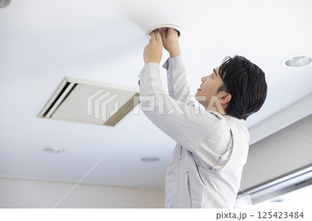 ビルメンテナンス　電球を交換する作業着姿の男性 125423484