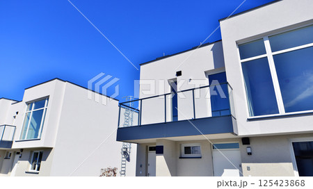 Terraced family homes in newly developed housing estate. The real estate market in the suburbs. New single family houses in a new development area. Residential homes with modern facade.  125423868