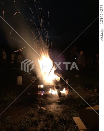 大きなキャンプファイヤーを囲む大人たち 125424278