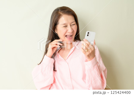 スマホを手に持つシニア女性 125424400