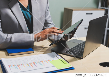 Working from home, Closeup business woman using laptop computer and analyzing financial report. Working from home, Closeup business woman using laptop computer and analyzing financial report. 125424692