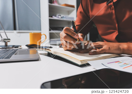 Working from home, Closeup business woman using laptop computer and analyzing financial report. 125424720