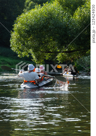 Family with children on rafting trip in Group kayak trip of different ages, adults, elderly. Rowing boat on the river, a water hike, summer adventure. 125424930