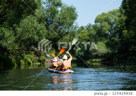 Family with children on rafting trip in Group kayak trip of different ages, adults, elderly. Rowing boat on the river, a water hike, summer adventure. 125424938