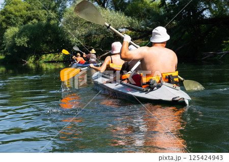 Family with children on rafting trip in Group kayak trip of different ages, adults, elderly. Rowing boat on the river, a water hike, summer adventure. 125424943