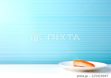 A beautifully presented plate of fresh salmon on a sleek, blue background. The vibrant pink-orange of the salmon contrasts perfectly with the cool tone of the plate and backdrop 125424947