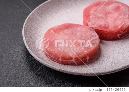 Two fresh slices of raw tuna fillet with spices and herbs Two fresh slices of raw tuna fillet with spices and herbs 125426421