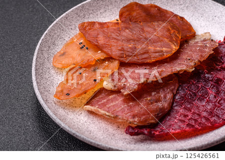 Jerky, dried meat in the form of slices with salt, spices and herbs Jerky, dried meat in the form of slices with salt, spices and herbs 125426561