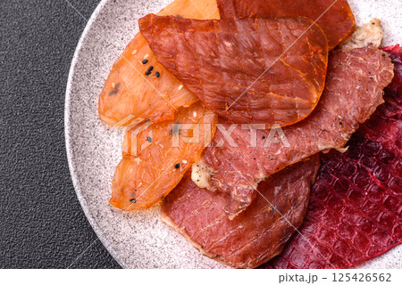 Jerky, dried meat in the form of slices with salt, spices and herbs Jerky, dried meat in the form of slices with salt, spices and herbs 125426562