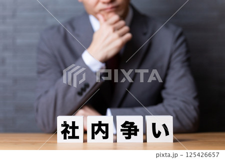 社内争いのブロックとスーツを着て悩むミドル男性ビジネスマン 125426657