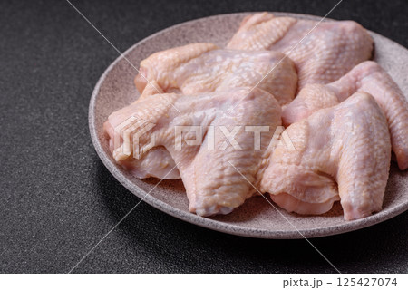 Raw chicken wings with salt, spices and herbs Raw chicken wings with salt, spices and herbs 125427074