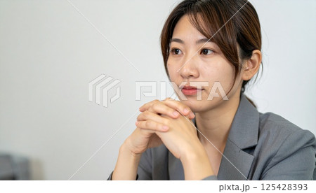 手を組んで考え込む女性ビジネスマン 手を組んで考え込む女性ビジネスマン 125428393