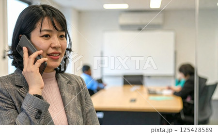 笑顔で電話、仕事に打ち込む女性 125428589