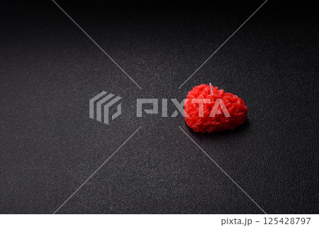 Red wax candle in the shape of a heart as decor for Valentine's Day 125428797