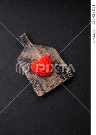 Red wax candle in the shape of a heart as decor for Valentine's Day 125428811
