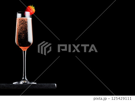 Elegant glass of pink rose champagne with strawberry on top on black marble board on black Elegant glass of pink rose champagne with strawberry on top on black marble board on black 125429111