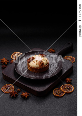 Sweet round tart with white citrus cream and pecans 125429406