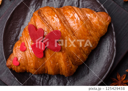 Sweet crispy croissant decorated with red hearts Sweet crispy croissant decorated with red hearts 125429438