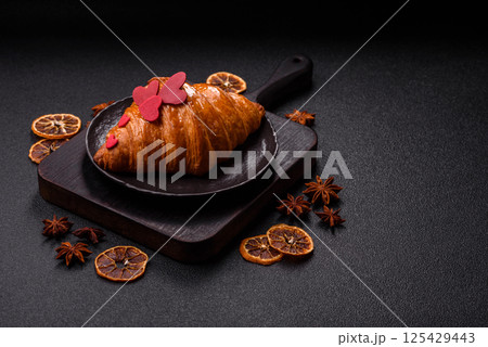 Sweet crispy croissant decorated with red hearts 125429443