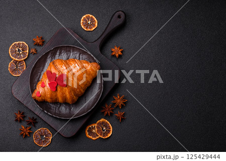 Sweet crispy croissant decorated with red hearts 125429444