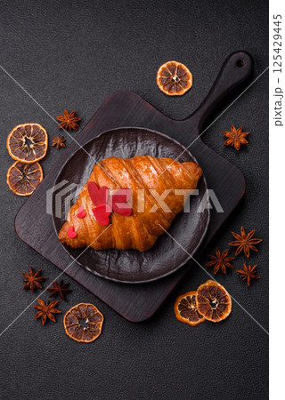 Sweet crispy croissant decorated with red hearts 125429445