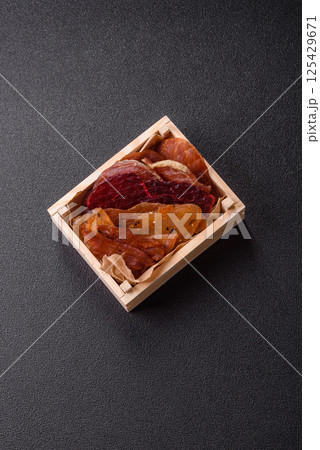 Jerky, dried meat in the form of slices with salt, spices and herbs Jerky, dried meat in the form of slices with salt, spices and herbs 125429671