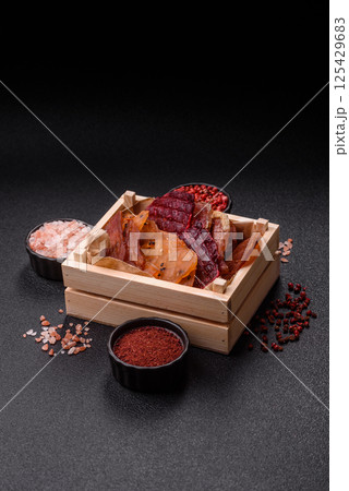 Jerky, dried meat in the form of slices with salt, spices and herbs Jerky, dried meat in the form of slices with salt, spices and herbs 125429683