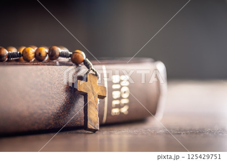 Wooden rosary beads and Holy Bible on wooden table. 125429751