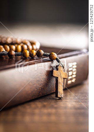 Wooden rosary beads and Holy Bible on wooden table. Wooden rosary beads and Holy Bible on wooden table. 125429752