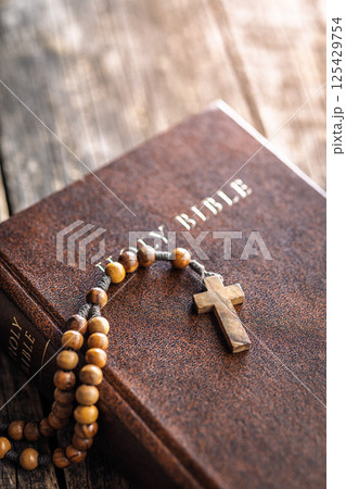 Wooden rosary beads and Holy Bible on wooden table. Wooden rosary beads and Holy Bible on wooden table. 125429754