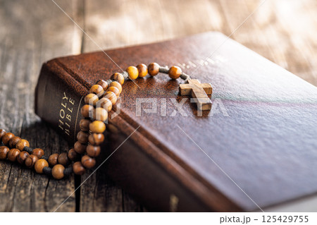 Wooden rosary beads and Holy Bible on wooden table. Wooden rosary beads and Holy Bible on wooden table. 125429755