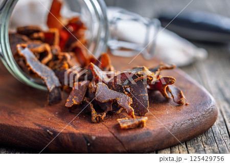 Beef jerky. Dried spiced meat on wooden table. 125429756