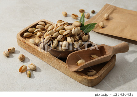 Pistachios in a wooden plate, on a light background. Pistachios in a wooden plate, on a light background. 125430435