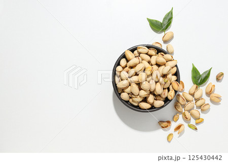 Pistachios in the shell with leaves, on a light background. Pistachios in the shell with leaves, on a light background. 125430442