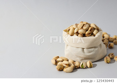 Pistachios in a fabric bag, on a green background. Pistachios in a fabric bag, on a green background. 125430443
