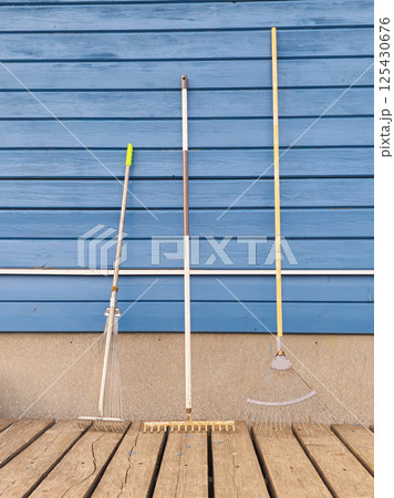 different garden rake near blue wooden wall different garden rake near blue wooden wall 125430676