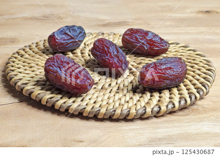 Ripe dates on a round rattan napkin Ripe dates on a round rattan napkin 125430687