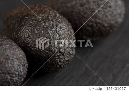 whole avocado fruits of small size on a black slate whole avocado fruits of small size on a black slate 125431037