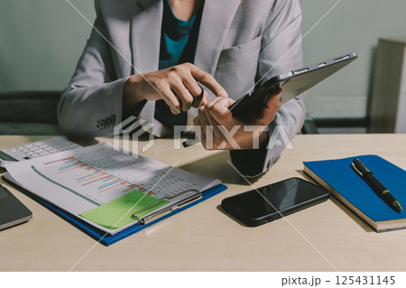 Working from home, Closeup business woman using laptop computer and analyzing financial report. 125431145