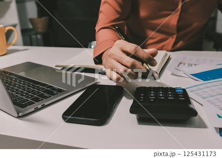 Working from home, Closeup business woman using laptop computer and analyzing financial report. 125431173