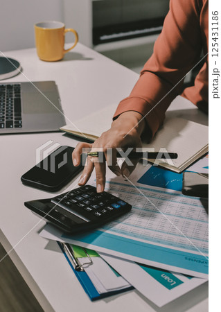 Working from home, Closeup business woman using laptop computer and analyzing financial report. 125431186