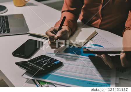 Working from home, Closeup business woman using laptop computer and analyzing financial report. 125431187