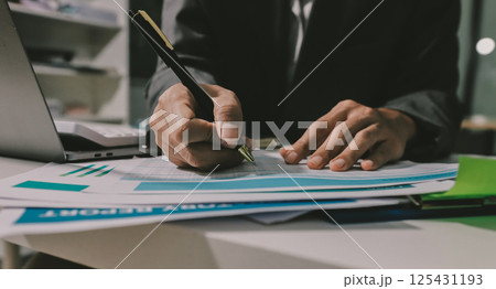Working from home, Closeup business woman using laptop computer and analyzing financial report. 125431193
