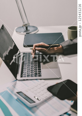 Working from home, Closeup business woman using laptop computer and analyzing financial report. Working from home, Closeup business woman using laptop computer and analyzing financial report. 125431216
