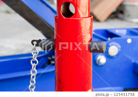 Close-up of the adjustable height locking pin and support column of a red jack stand Close-up of the adjustable height locking pin and support column of a red jack stand 125431738