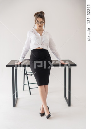 Businesswoman Leaning on Desk, White Shirt and Black Skirt, Isolated Studio Shot Businesswoman Leaning on Desk, White Shirt and Black Skirt, Isolated Studio Shot 125432246