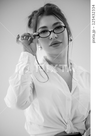 Black and White Portrait of a Young Woman with Glasses in a White Shirt Black and White Portrait of a Young Woman with Glasses in a White Shirt 125432334