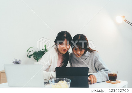 Female higher education student using laptop and studying book in home, Online learning. Female higher education student using laptop and studying book in home, Online learning. 125432700